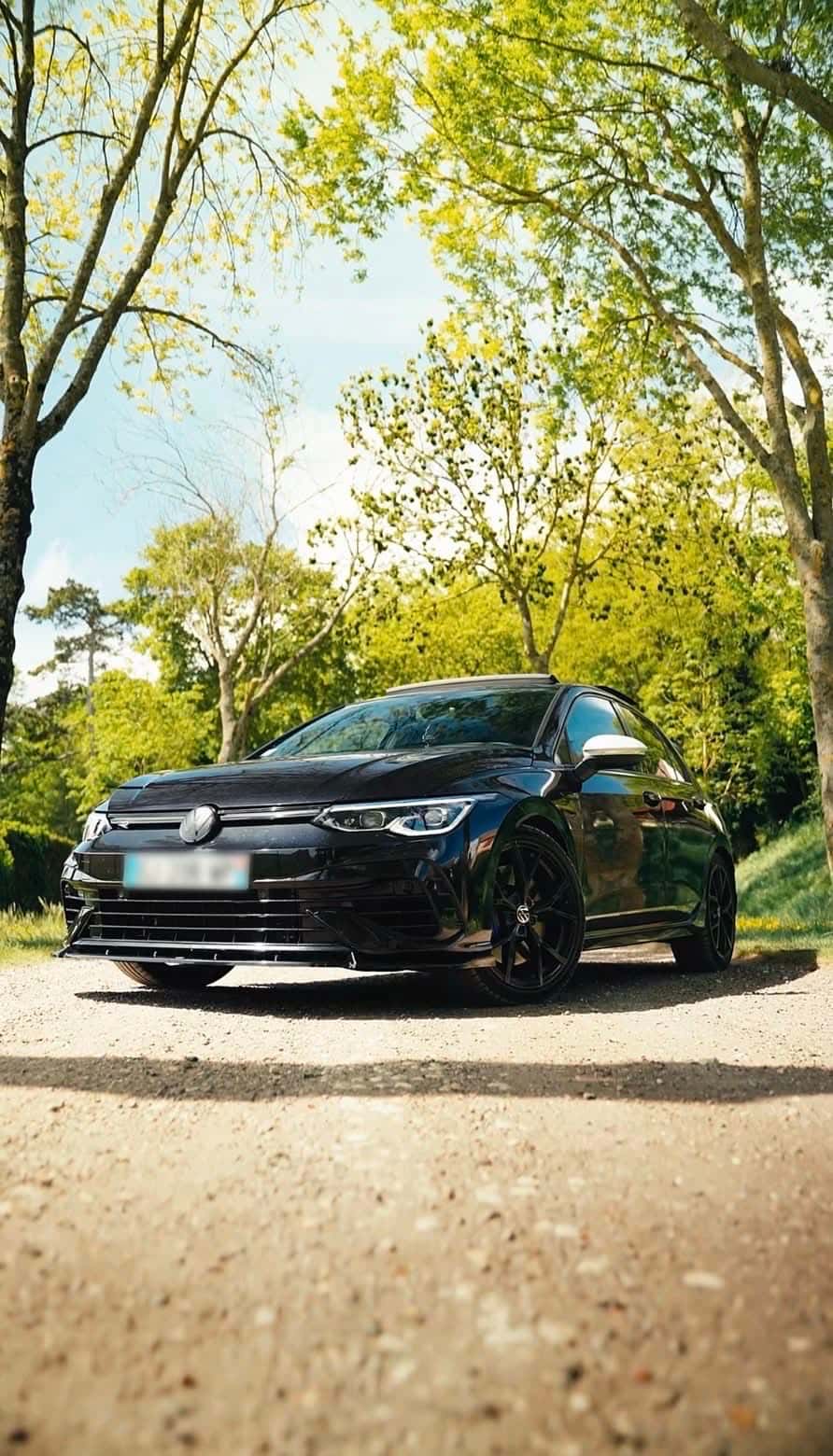 Volkswagen Golf 8 R noire de RS Prestige Car dans une allée boisée, lumière dorée de fin de journée